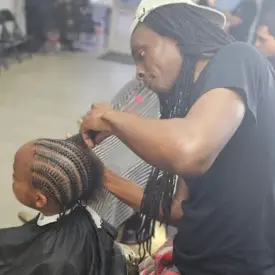 A client getting their hair braided in the corn row style