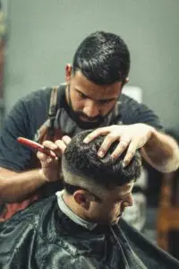 A barber putting the finishing touches on a haircut with a razor